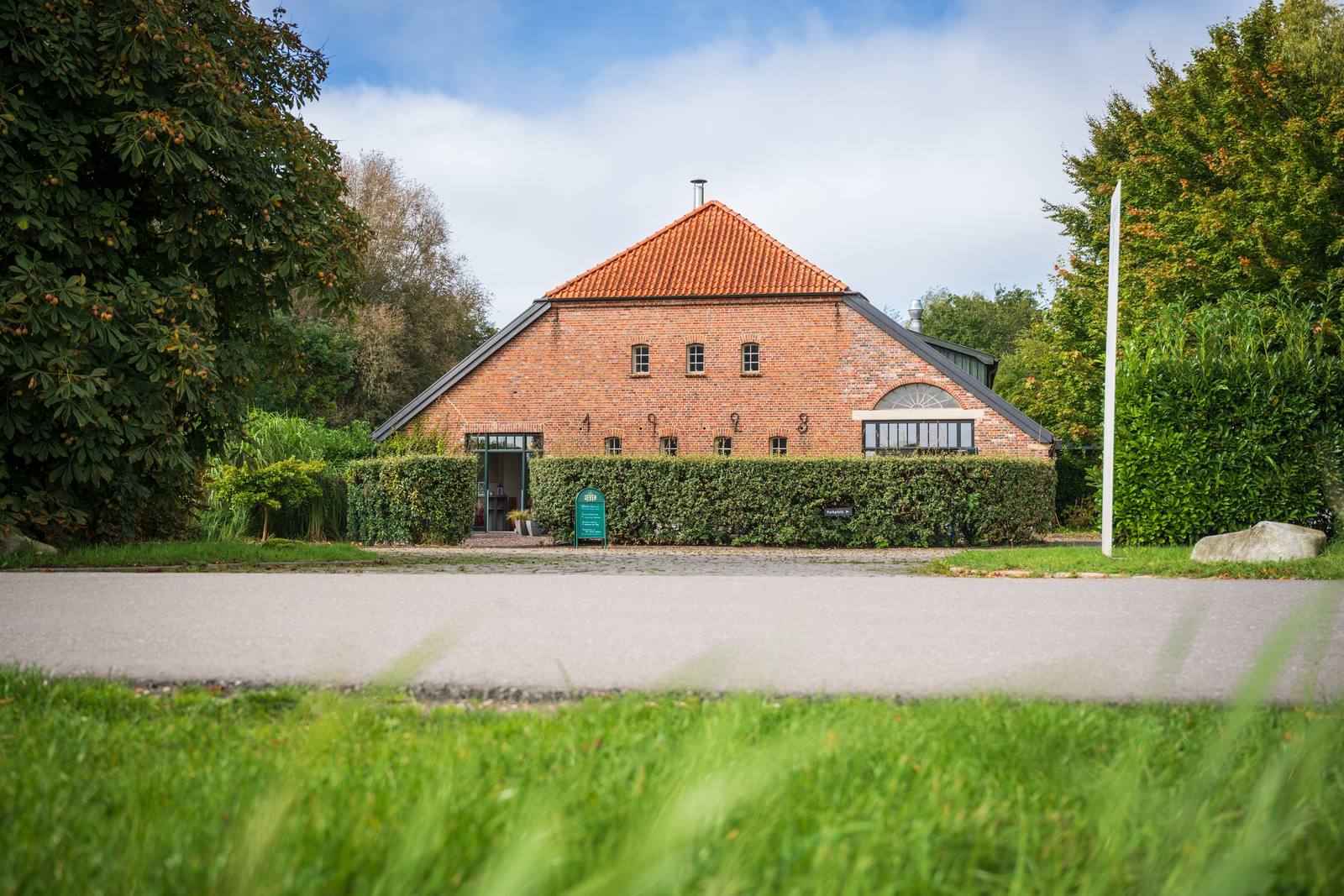 Der friesische Gulfhof des Land- und Wellnesshotels NAKUK, umgeben von altem Baumbestand